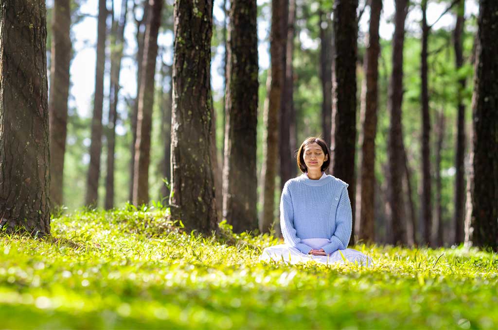 Mujer práctica mindfullness en el bosque.