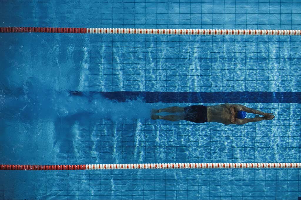 Hombre nadando piscina olímpica.