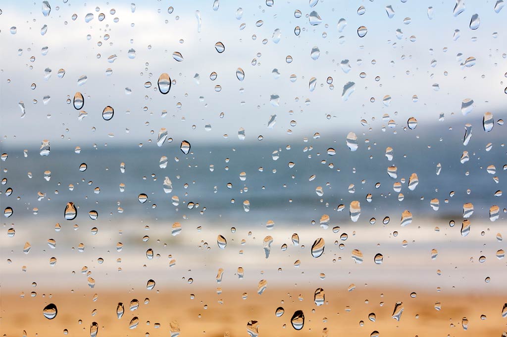 Playa a través de la ventana en un día lluvioso.