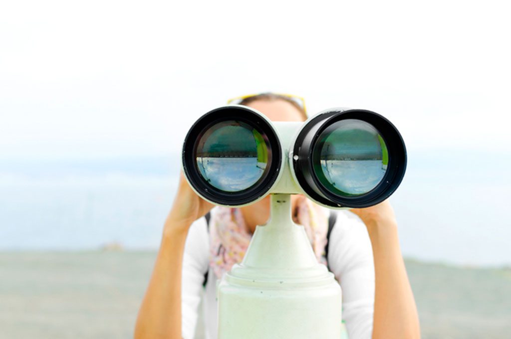 Una mujer observa con binoculares en primer plano.