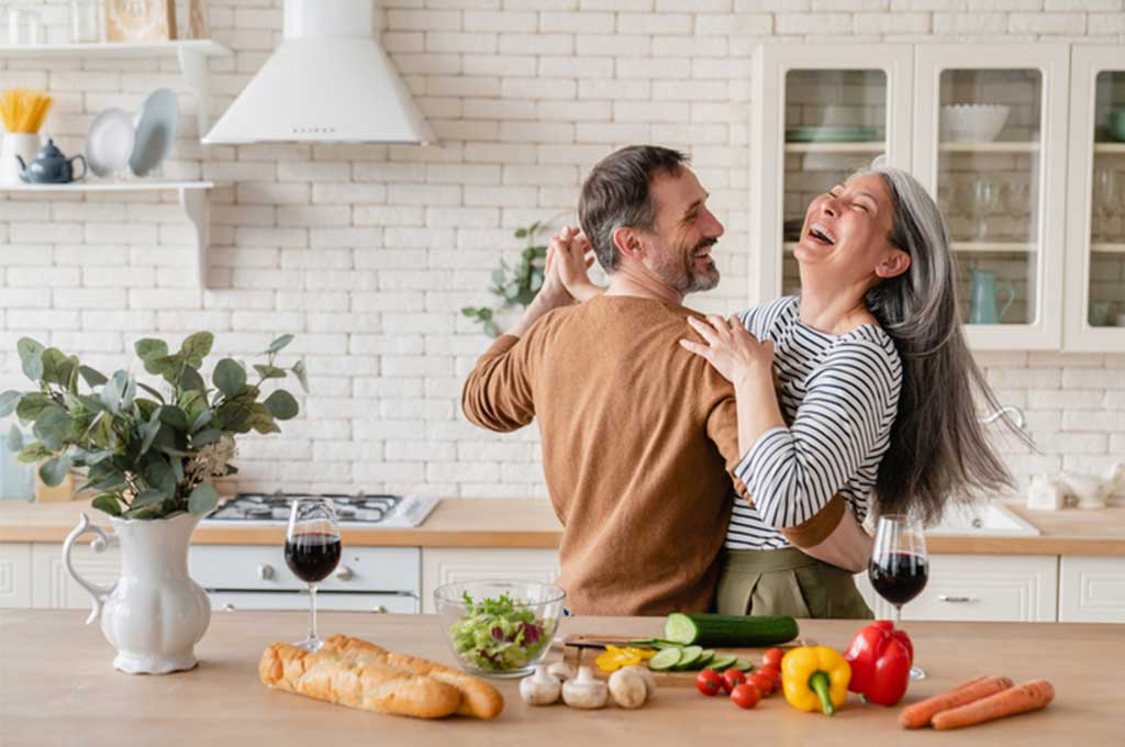 Una pareja feliz bailando en la cocina.